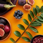 Top view of colorful fruits and vegetables on a vibrant orange background, perfect for healthy lifestyle concepts.