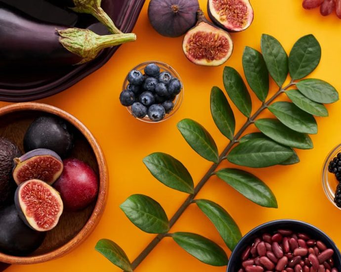 Top view of colorful fruits and vegetables on a vibrant orange background, perfect for healthy lifestyle concepts.