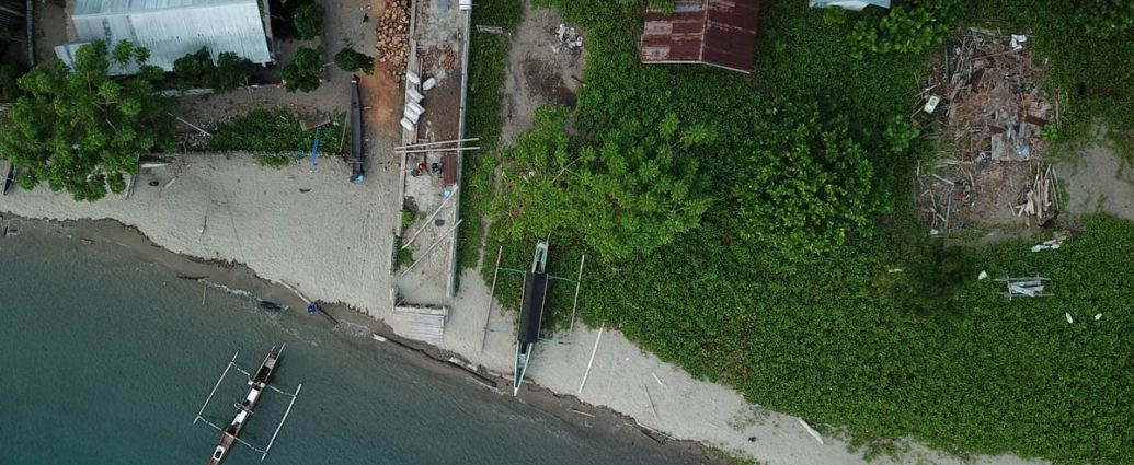 Drone shot capturing a coastal scene with boats and greenery in Una-Una, Indonesia.